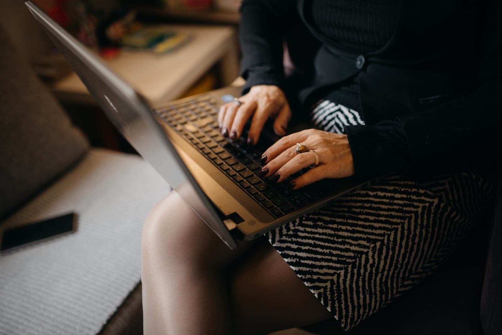 Professional hands in business attire typing on a laptop keyboard at a wooden desk